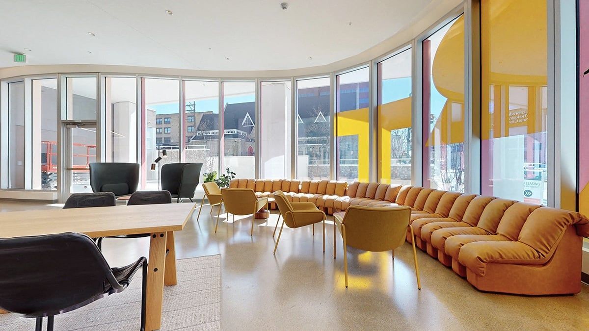 Modern lounge area with curved windows and mustard-colored seating.