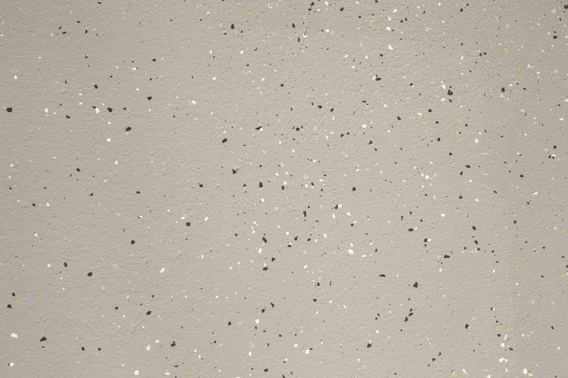 Light gray surface with scattered dark and silver flecks.