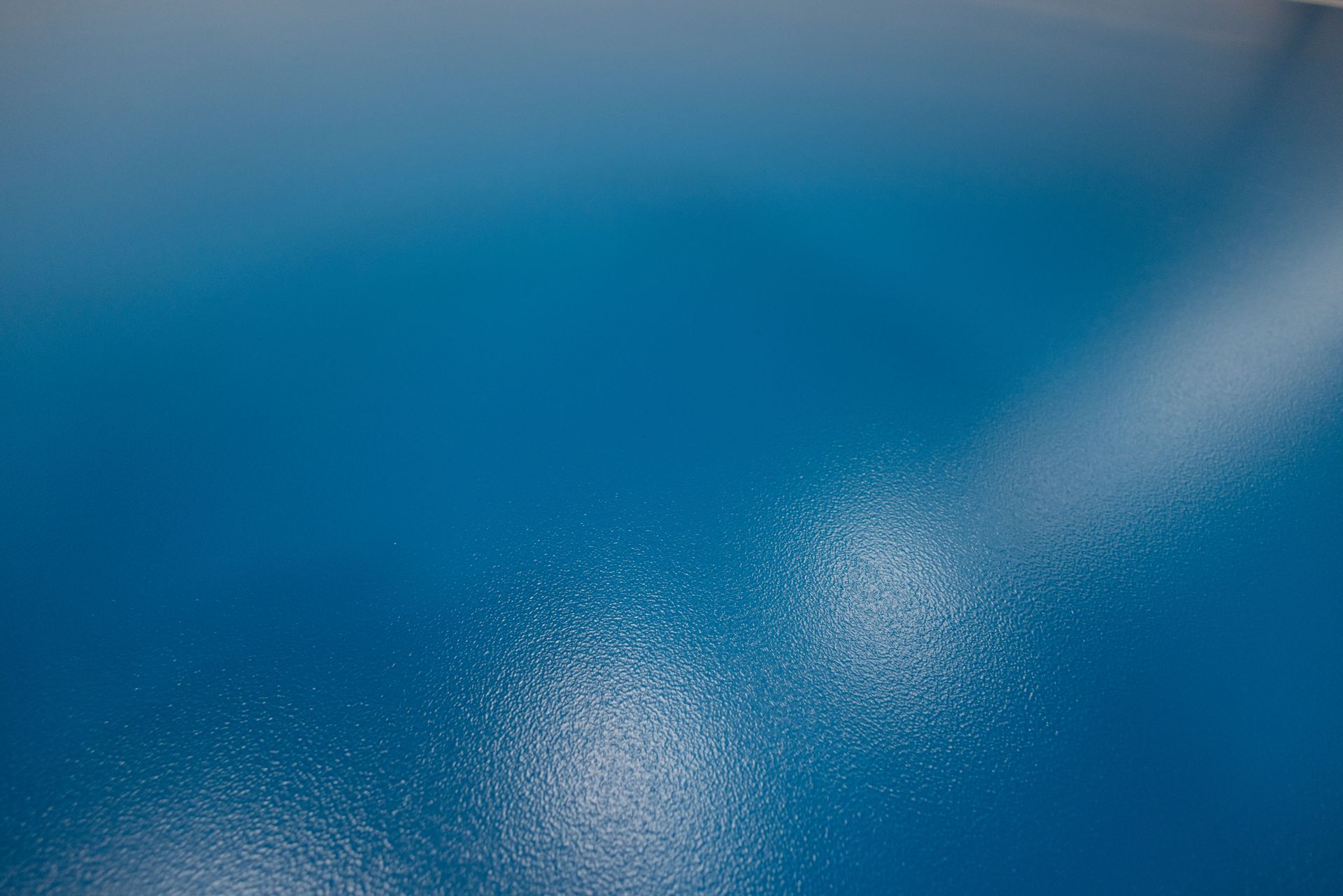 Blue surface with white speckled texture and a bright diagonal streak.