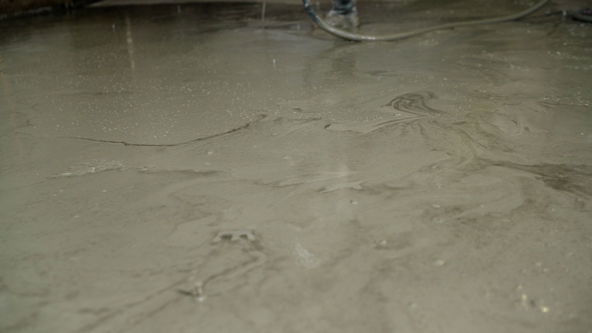 Wet concrete floor being finished with a smoothing tool.