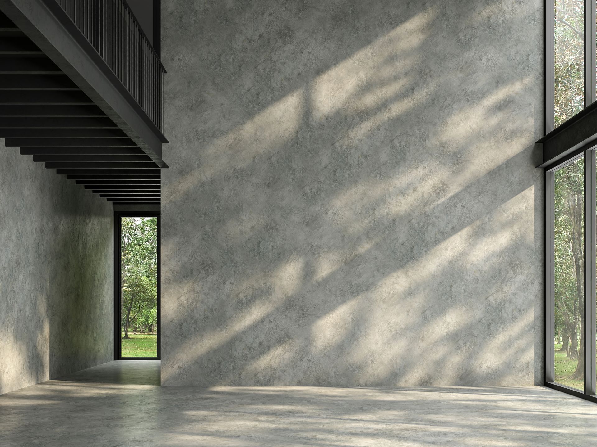 Concrete-walled, modern interior with large windows and a second-story balcony. Sunlight and tree shadows on the wall.