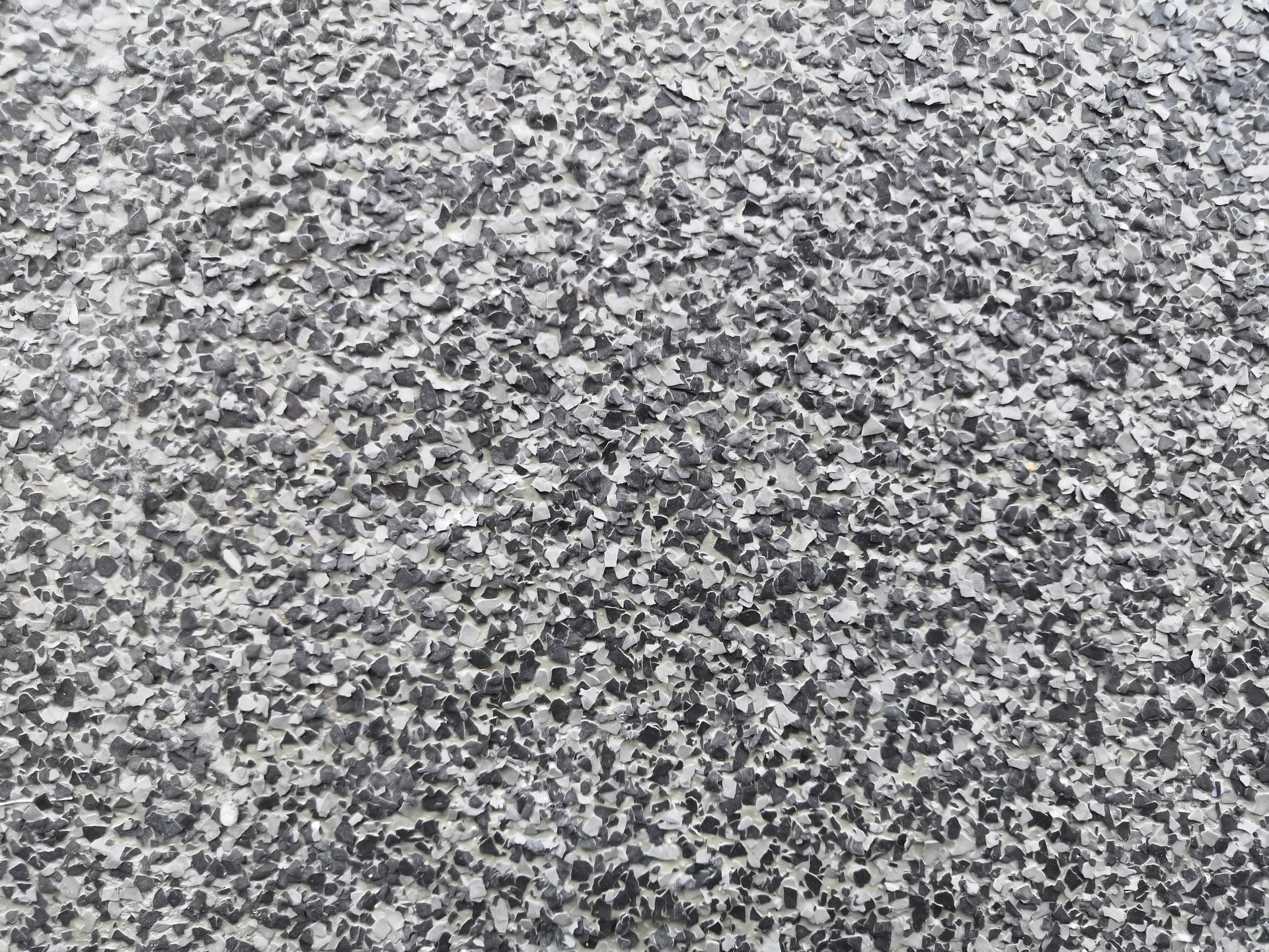 Close-up of a speckled, textured surface primarily composed of small, dark gray and light gray particles.