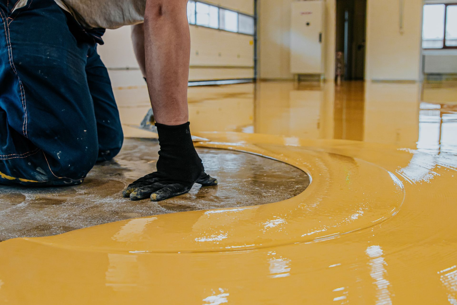 Person applying yellow epoxy coating to a floor.