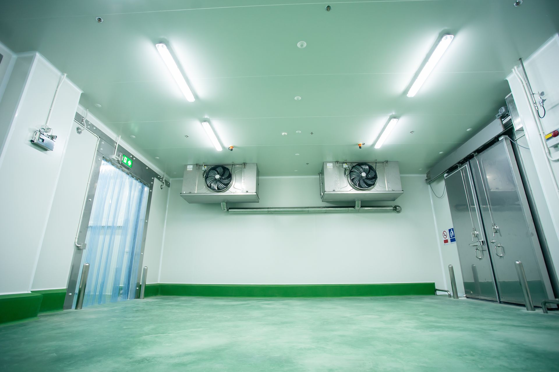 Cold storage room interior with overhead lights, refrigeration units, and two sliding doors.