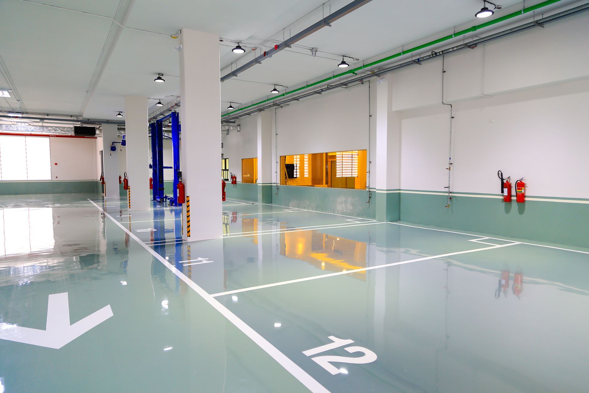 Bright, clean auto repair shop with numbered bays, a car lift, and fire extinguishers.