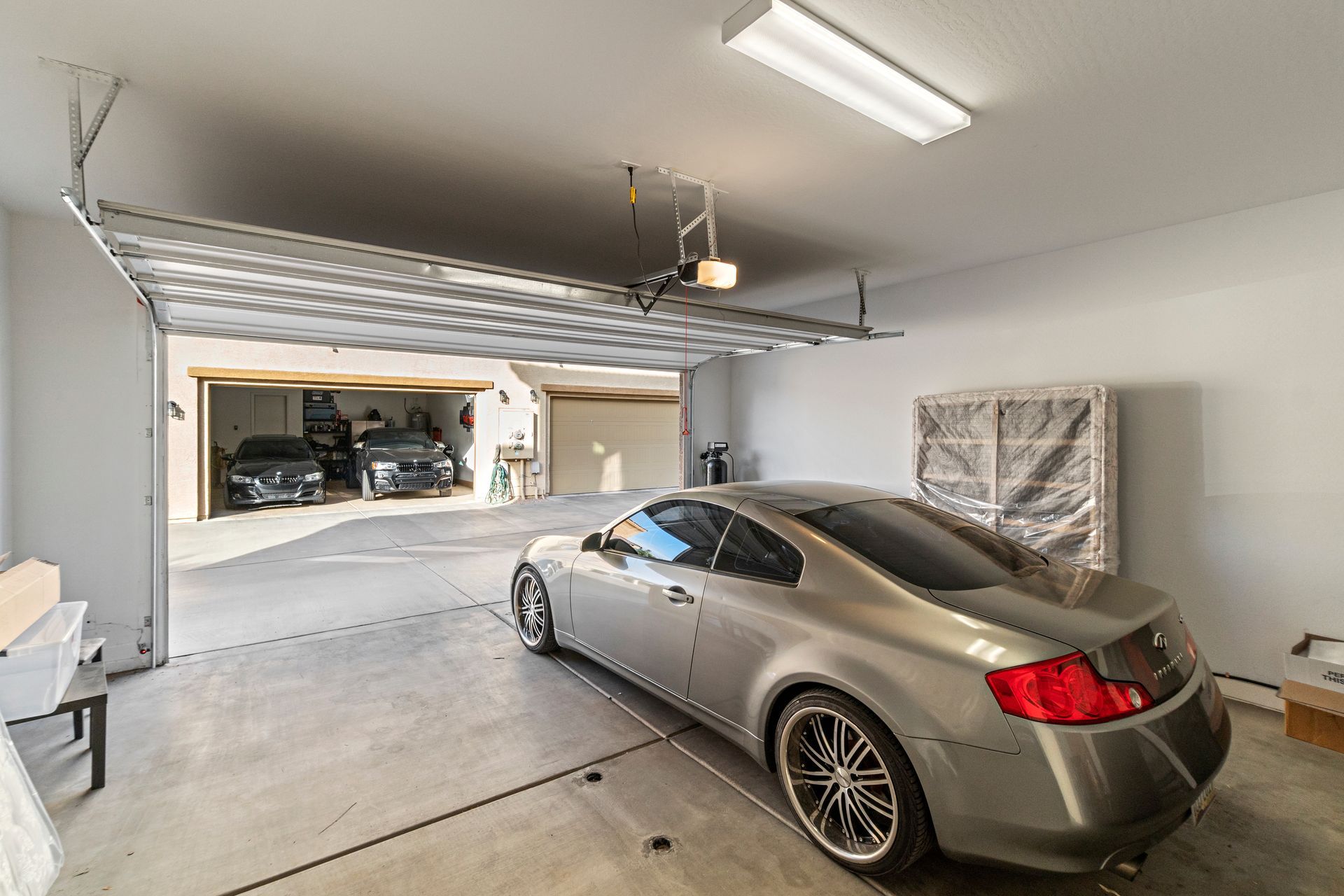Silver car parked in a garage with open doors, revealing two additional cars inside.