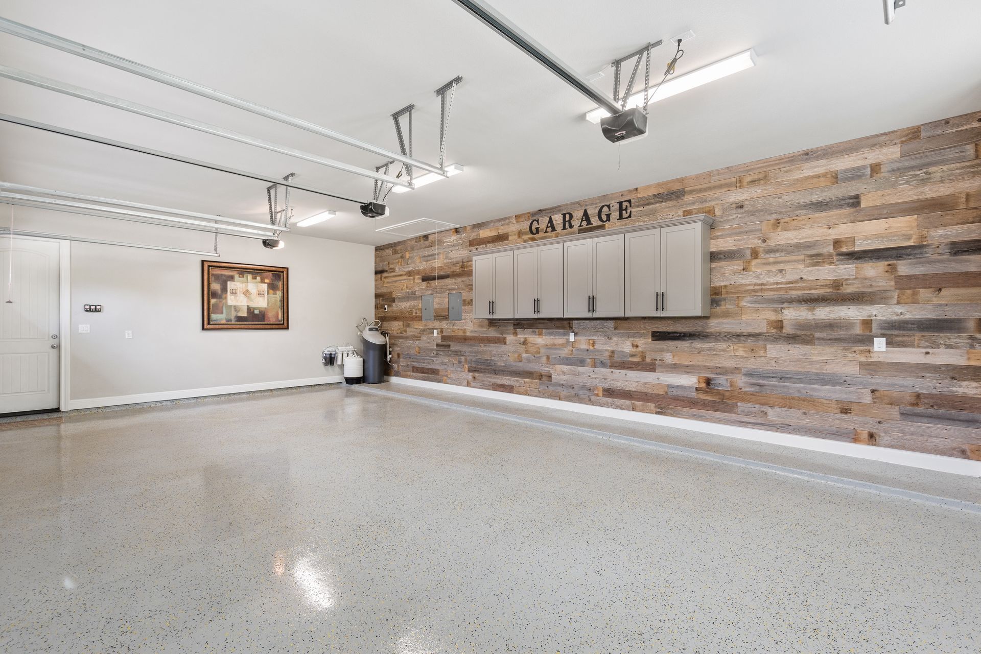 Spacious garage with wood plank accent wall, cabinets, and a polished concrete floor.