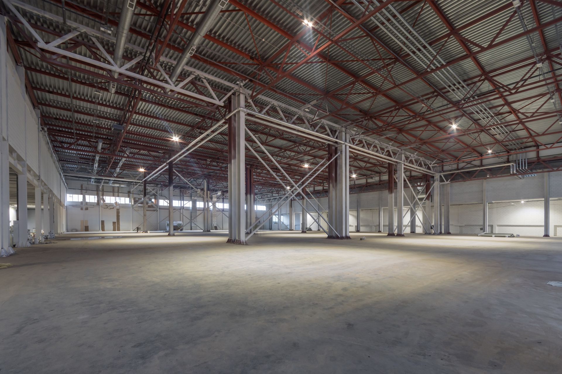Large, empty industrial warehouse with concrete floor and metal roof.