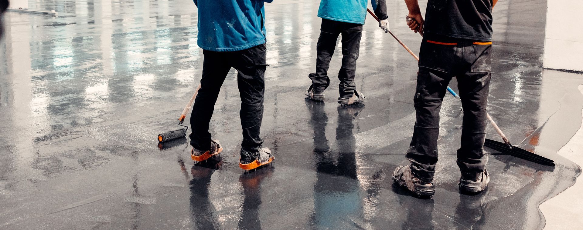 Three people sweeping a wet floor. Reflections are visible.