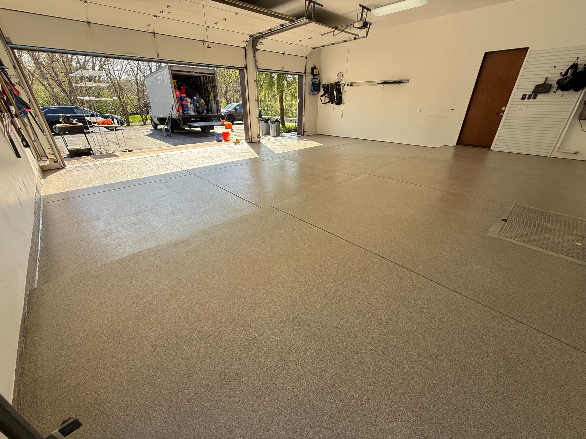 Spacious garage with beige tile floor, open door, and a wood door on the right.