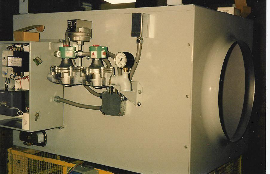 Gray industrial equipment with valves, gauges, and a large circular opening.