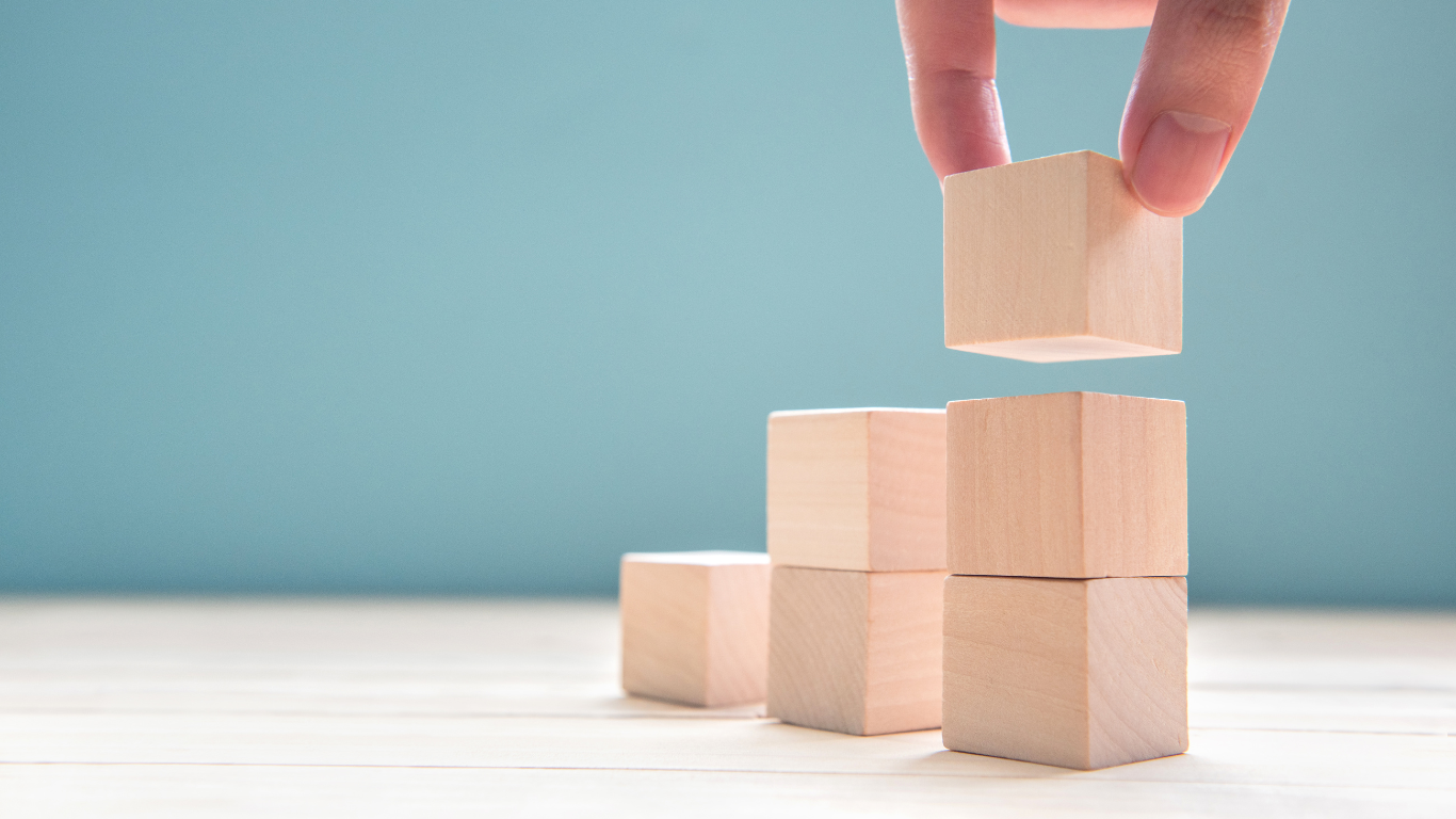 Close up businessman hand arranging wood cubes stacking symbolizing business growth and scalability