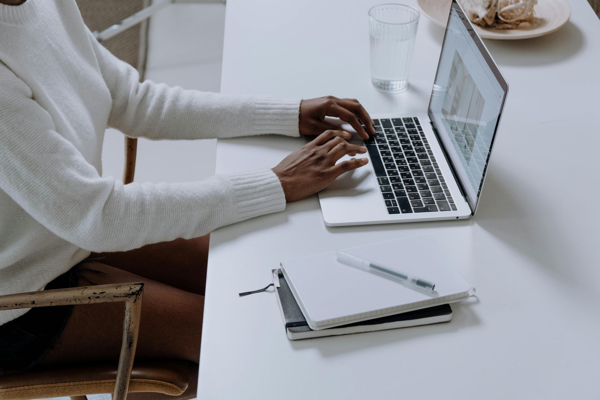 A Virtual Assistant is sitting at a desk typing on a laptop computer.