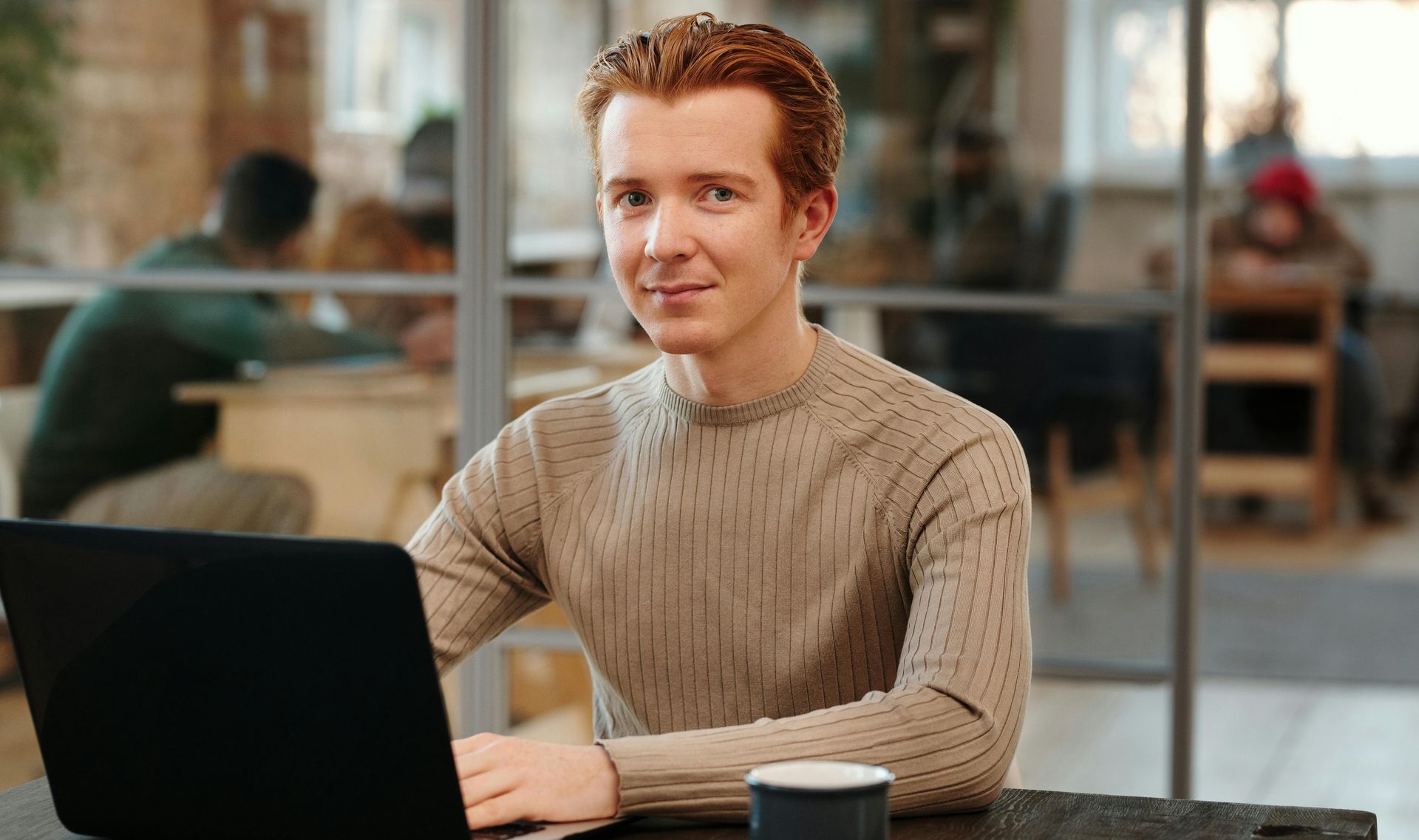 A man is sitting at a table using a laptop computer.