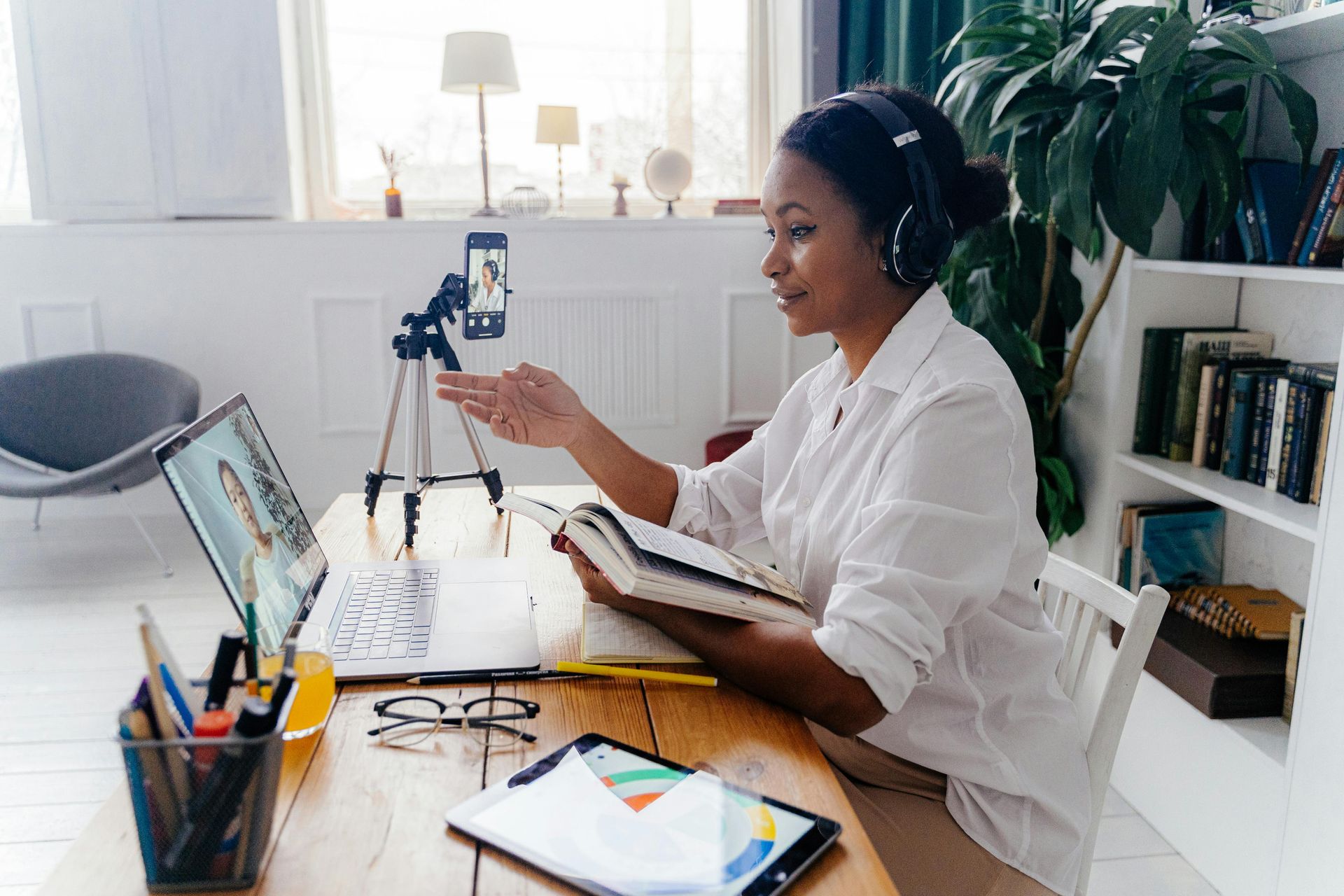 A woman is sitting at a table with a laptop and a tablet.