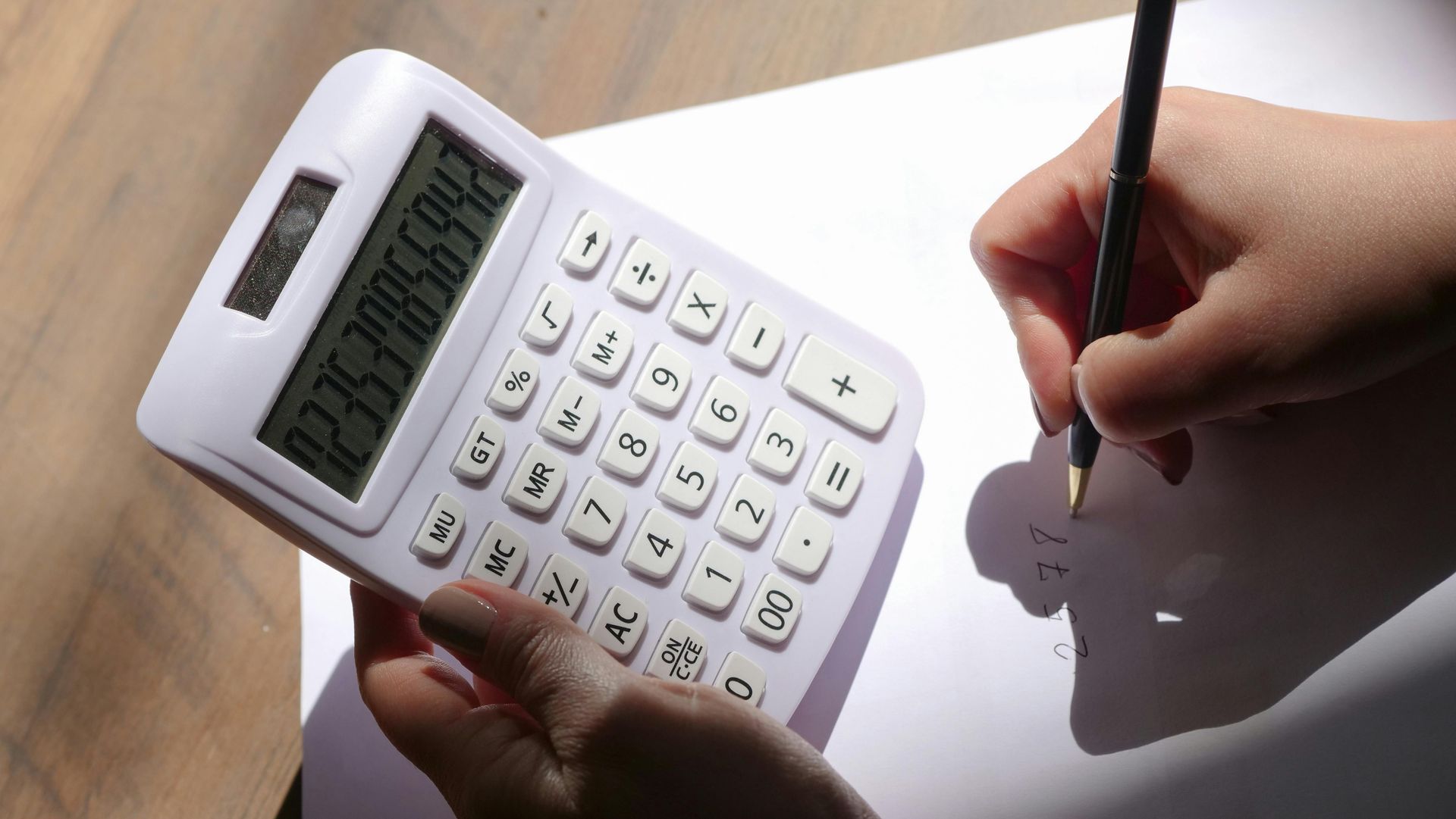 A Virtual Assistant is using a calculator and writing on a piece of paper