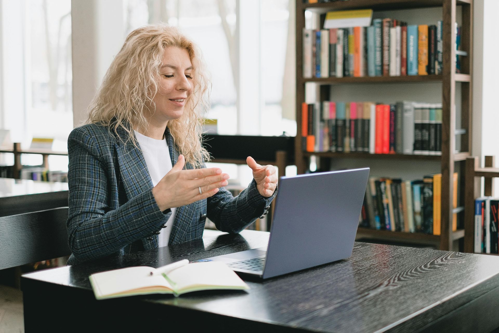 A woman is sitting at a table using a laptop computer.