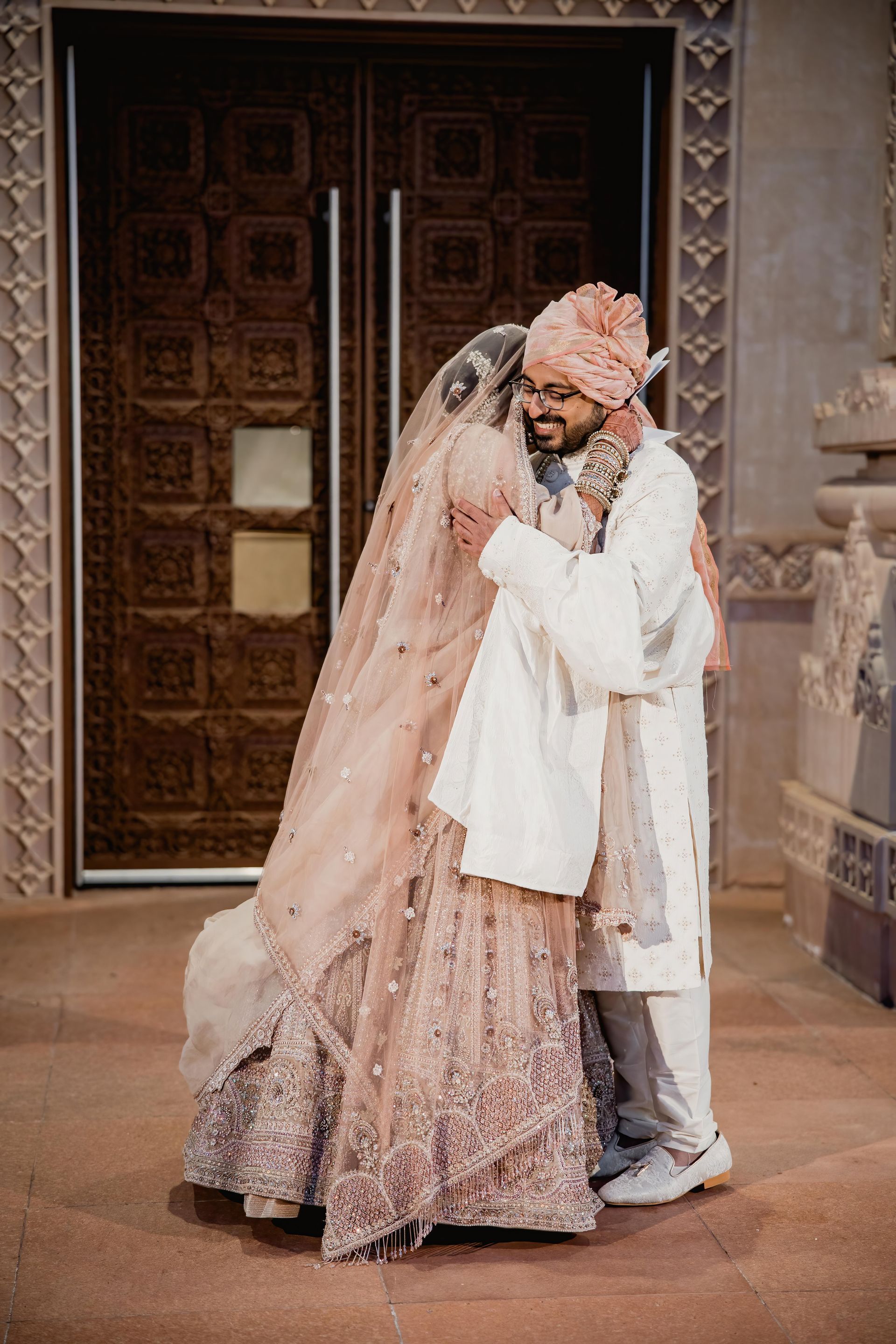 A bride and groom are hugging each other in front of a door.
