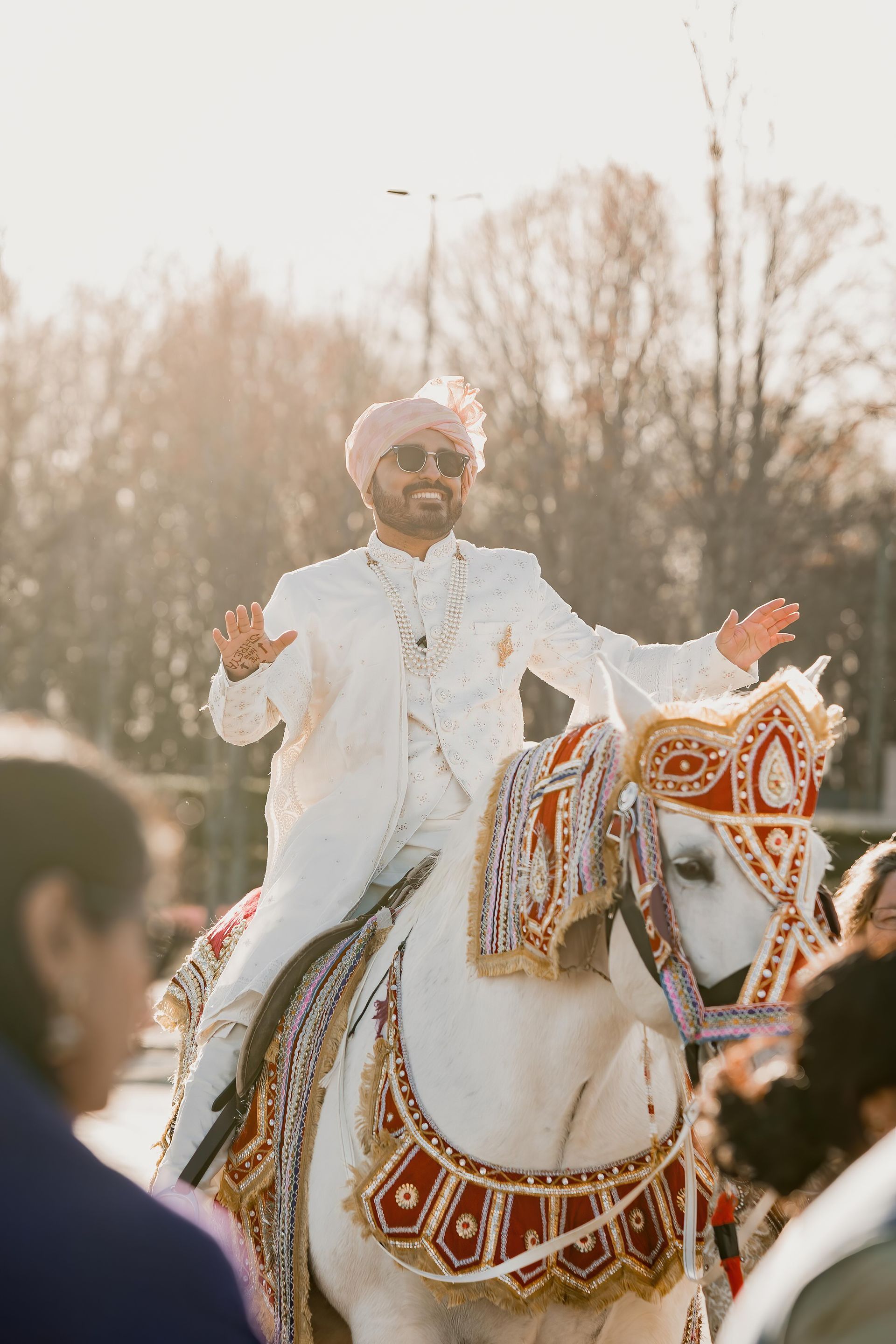 A man in a white suit is riding a white horse.
