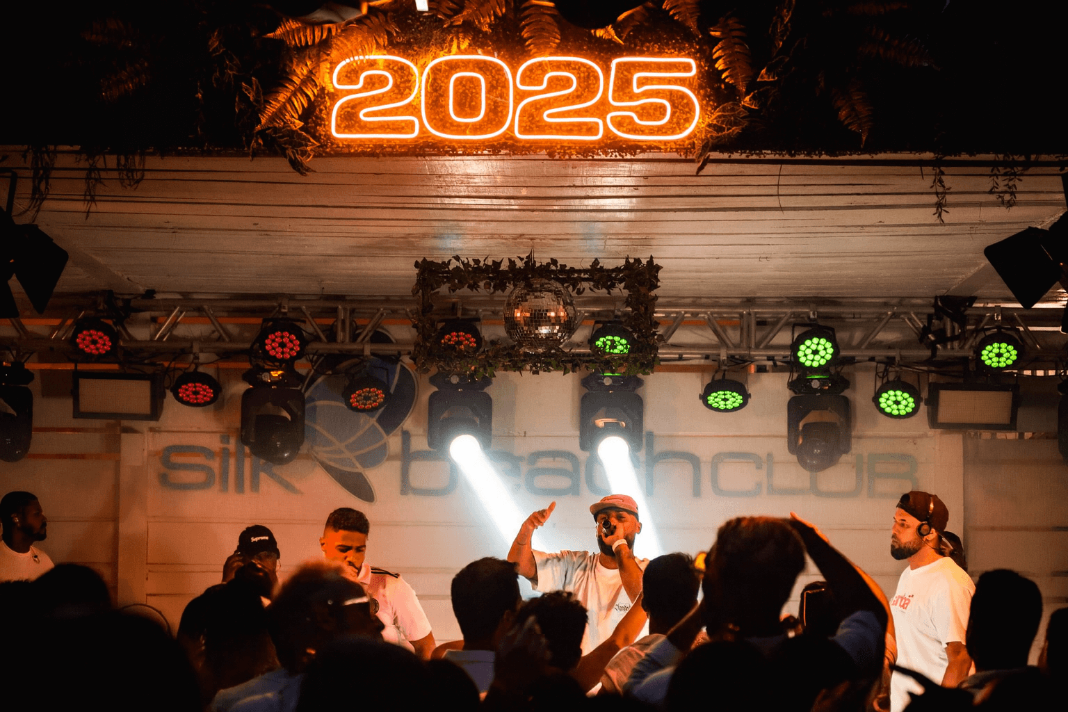 A concert at Silk Beach Club with performer on stage, orange neon 