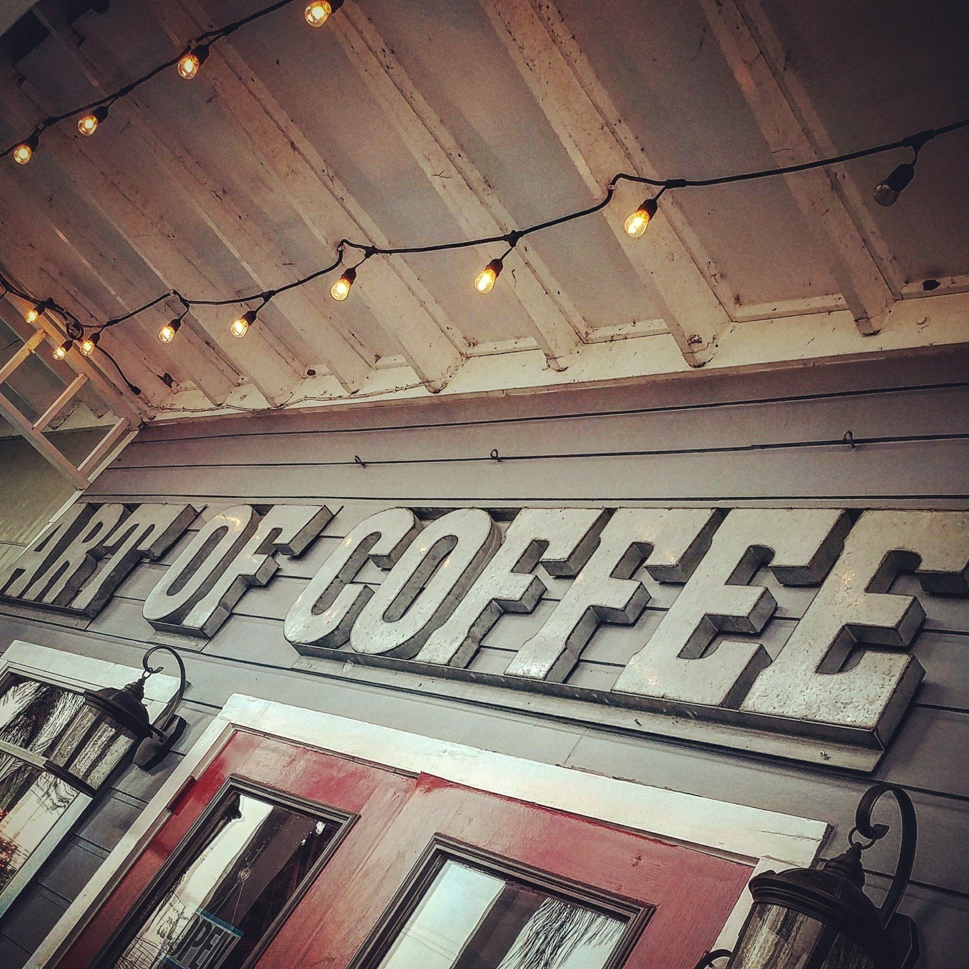 A sign on the side of a building that says art of coffee