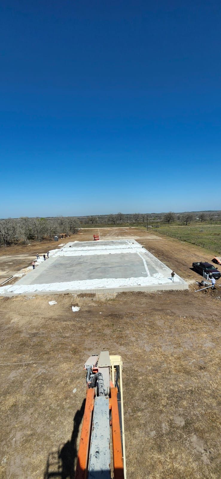 Construction site with a concrete foundation, machinery, and blue sky.