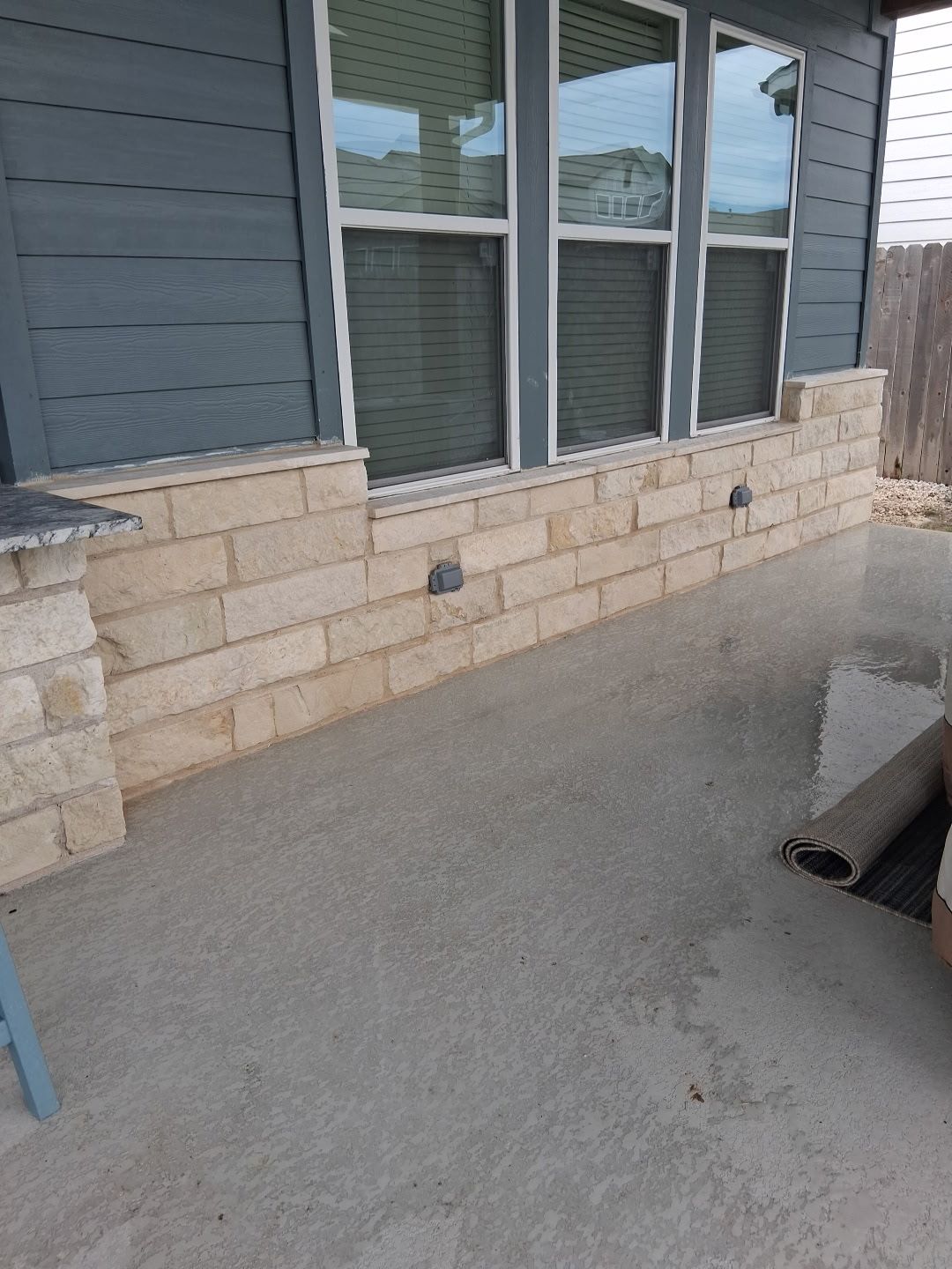 Stone patio wall with windows above, and concrete floor.