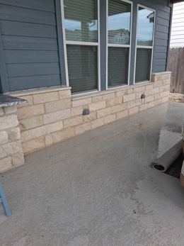Exterior patio with light-colored stone brickwork beneath windows and a concrete floor.