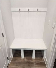 White entryway bench with three hooks and a vertical panel back.