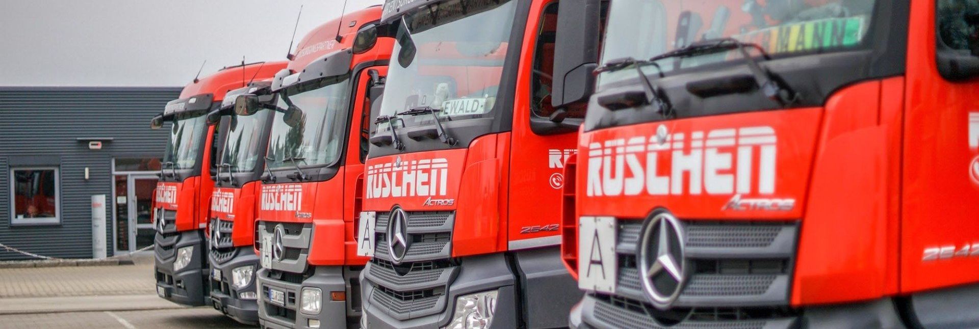 Auf einem Parkplatz steht eine Reihe roter Lastwagen nebeneinander.