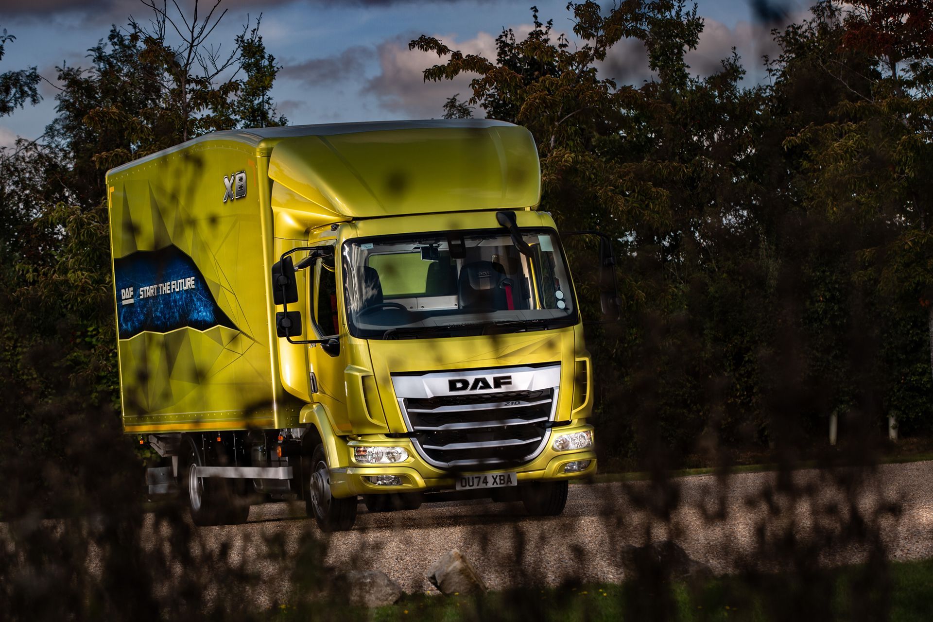 An Aesthetic Image of Yellow Rigid Truck A aesthetic image of yellow box truck parked on a roadway, showcasing zero-emission commercial transport technology.