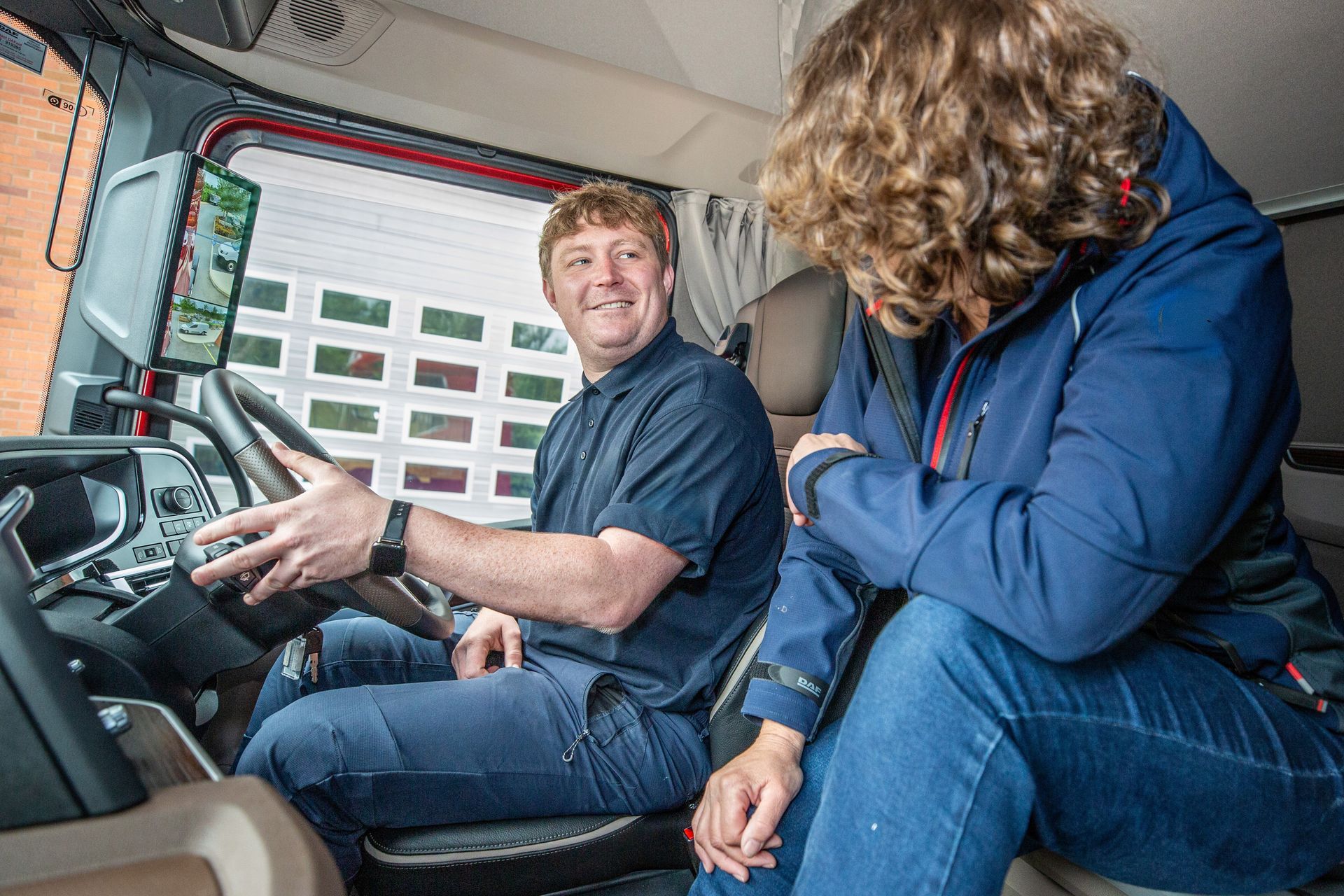 Truck Driver Demonstration of Digital Camera System in Modern Cab Truck driver demonstrating digital camera mirrors and safety technology inside a modern truck cab