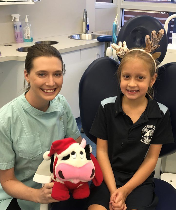 A Little Girl Is Sitting In A Dental Chair With A Stuffed Cow — BB Dental Cairns Dentists Dental In Earlville, QLD