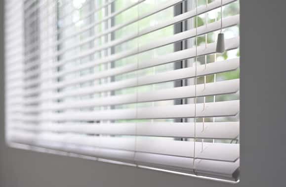 The Sun Is Shining Through the Blinds of A Window — Bay Blinds & Doors in Bateau Bay, NSW