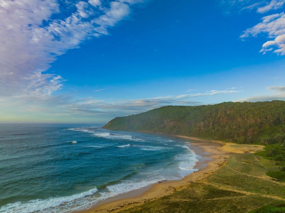 An aerial view of a beach with a mountain in the background — Bay Blinds & Doors in Bateau Bay, NSW