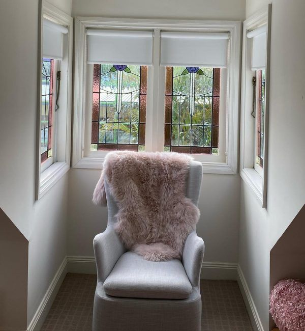 A Gray and White Striped Roman Shade Is Hanging on A Window — Bay Blinds & Doors in Kincumber, NSW