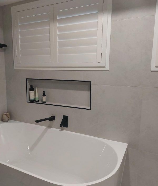 A Bathroom with A Bathtub and A Window with Shutters — Bay Blinds & Doors in Berkeley Vale, NSW