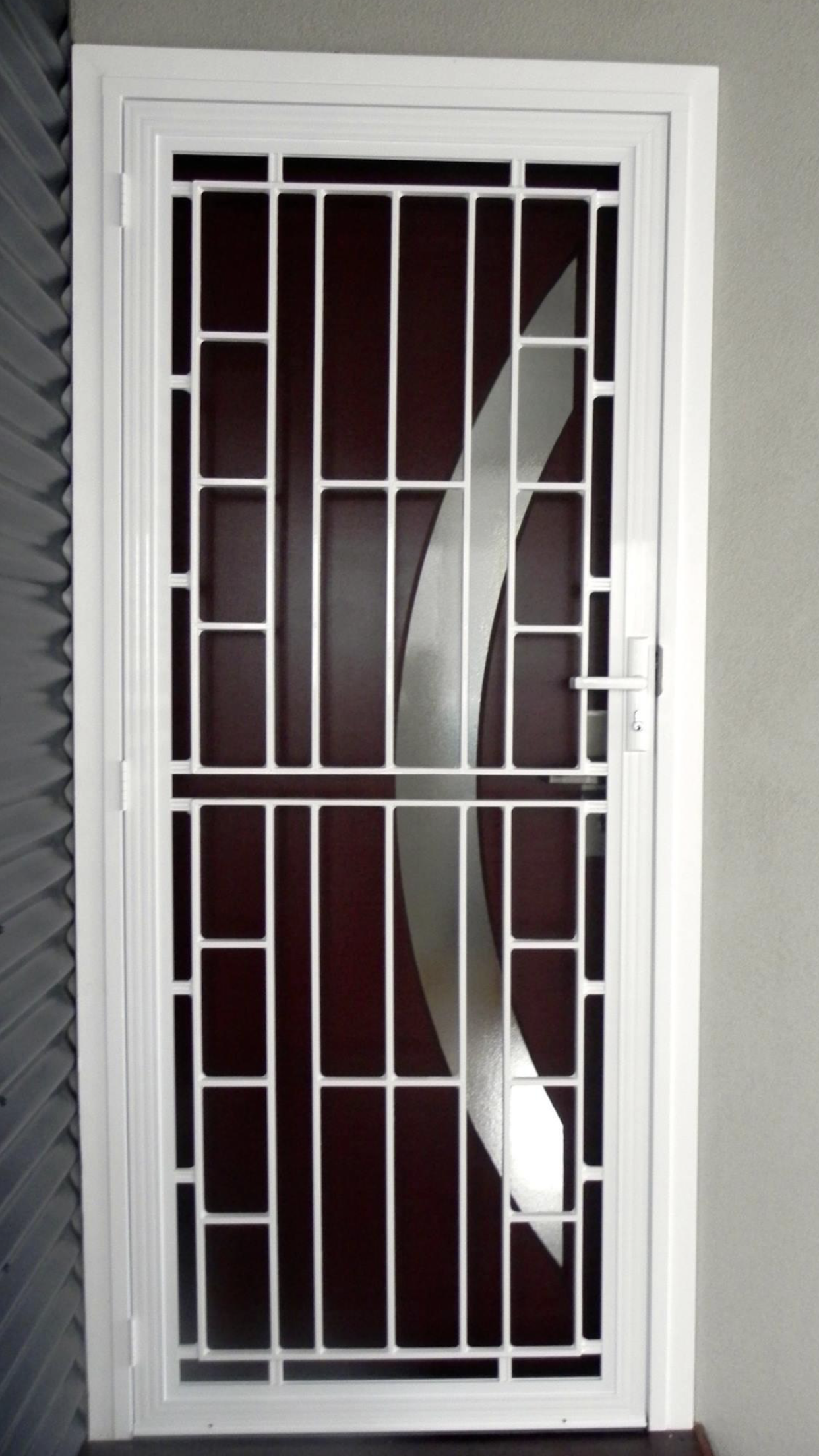 A Black and White Striped Awning Is Hanging on The Side of A Brick Building — Bay Blinds & Doors in Bateau Bay, NSW