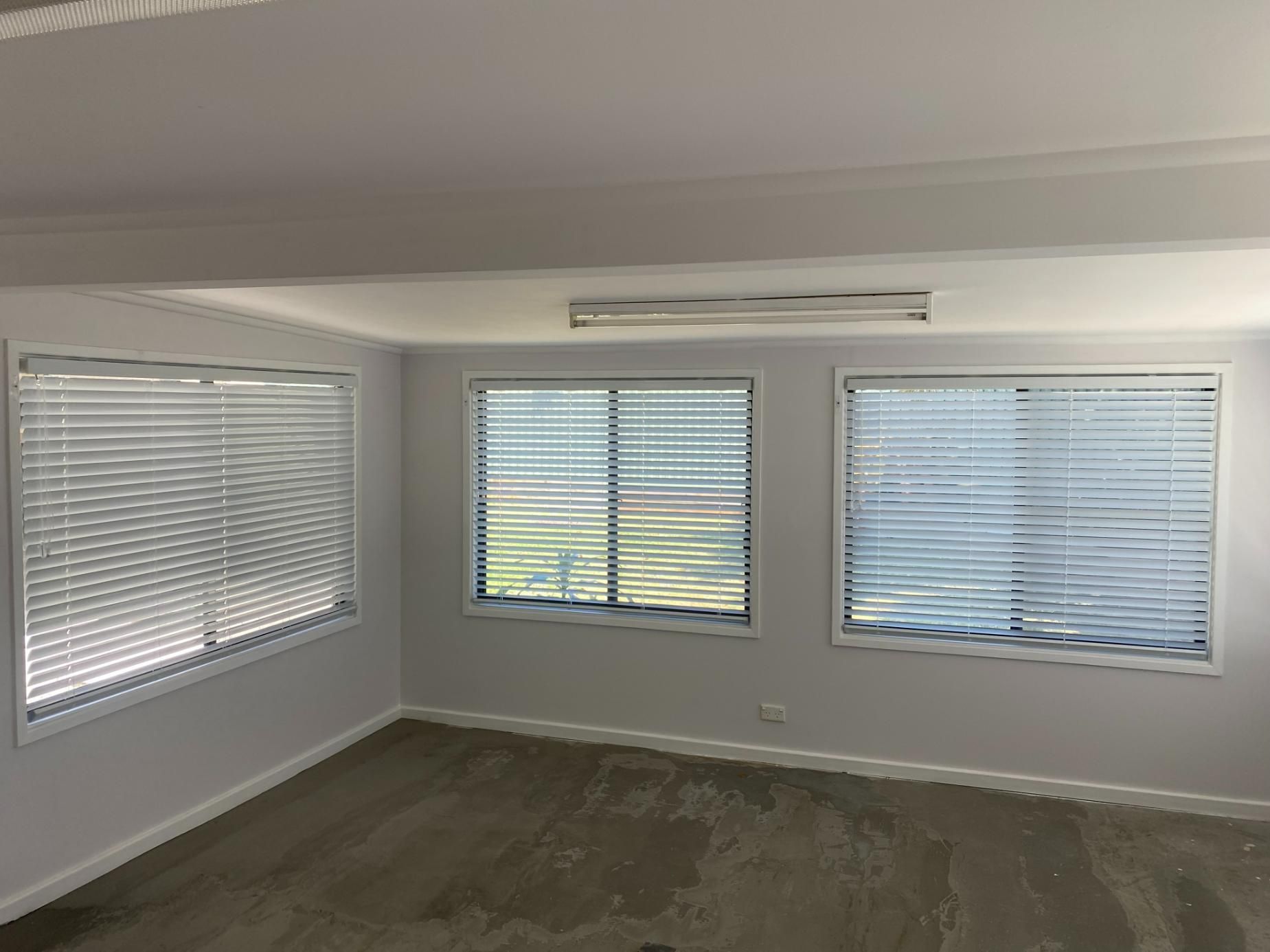 An Empty Room with Two Windows and Blinds on The Windows — Bay Blinds & Doors in Bateau Bay, NSW