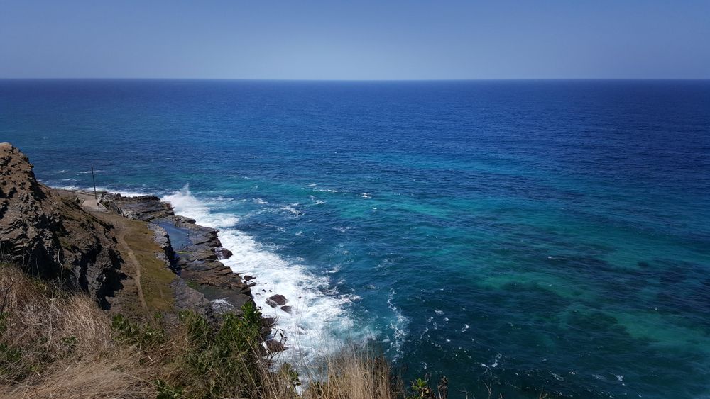 A view of the ocean from a cliff on a sunny day — Bay Blinds & Doors in Morisset, NSW