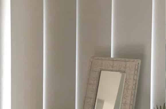 A Mirror Is Sitting on A Shelf Next to A Window with Blinds — Bay Blinds & Doors in Bateau Bay, NSW
