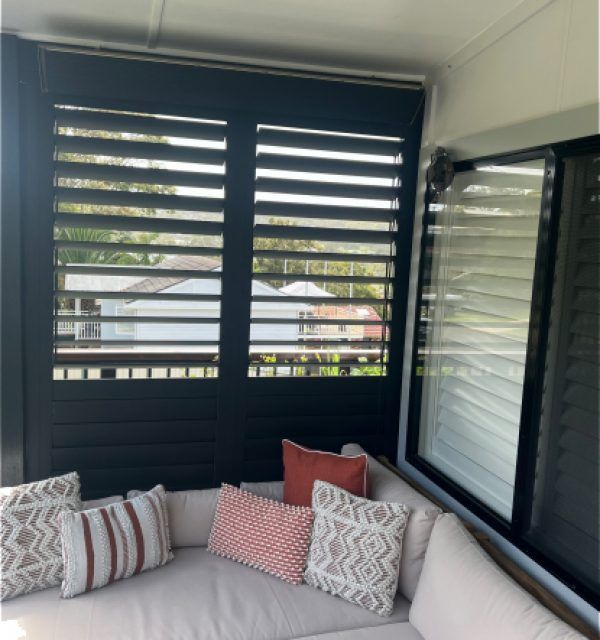 A Living Room with A Couch and Pillows in Front of A Window — Bay Blinds & Doors in Bateau Bay, NSW