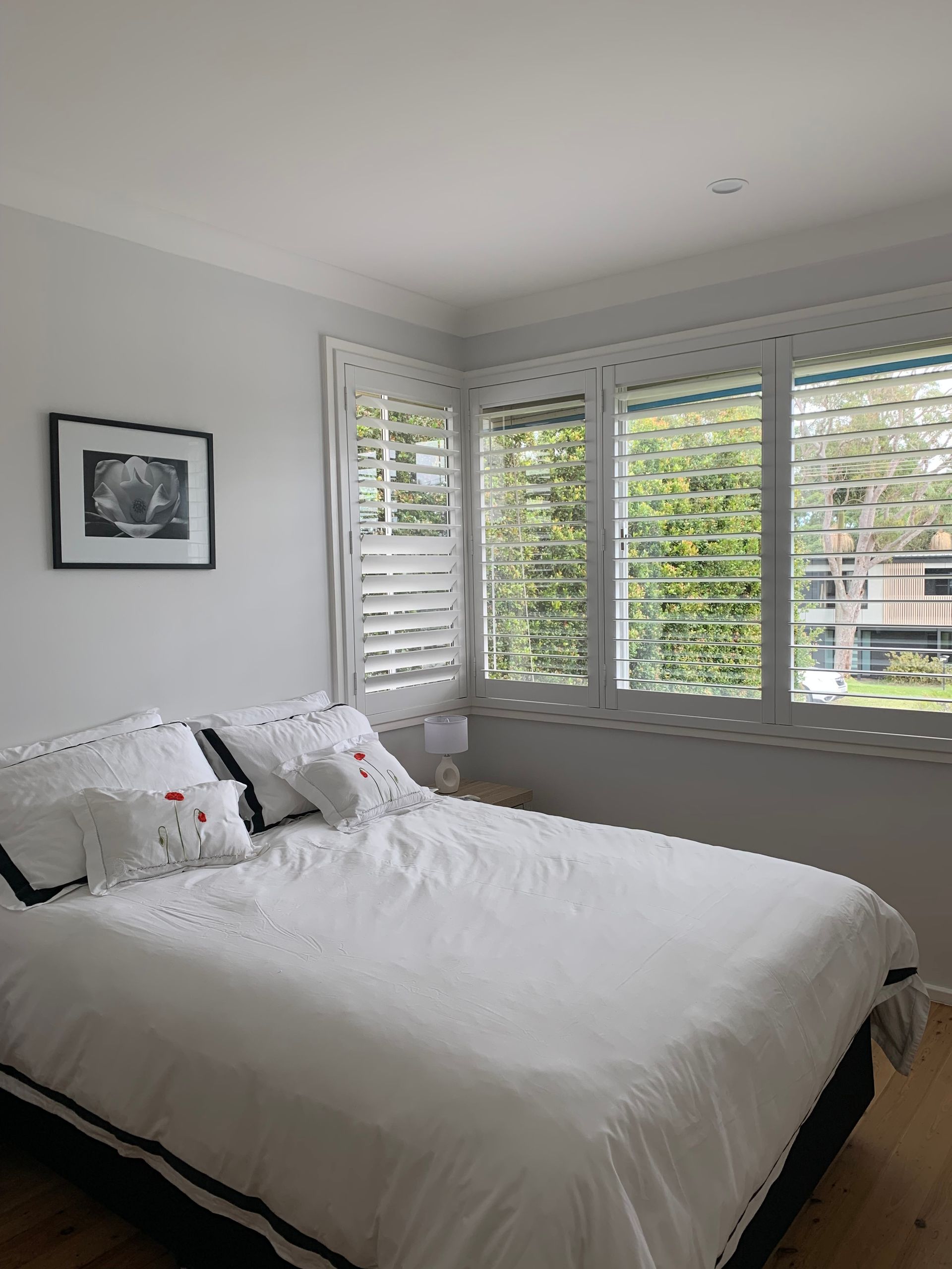 A Balcony with A Couch and Pillows and Shutters on The Windows — Bay Blinds & Doors in Woy Woy, NSW