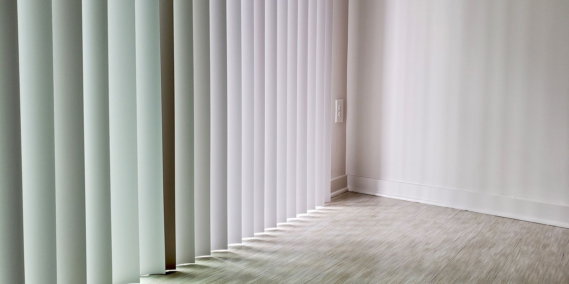 A Gray and White Striped Roman Shade is Hanging on a Window - Bay Blinds & Doors in Lake Charmhaven, NSW