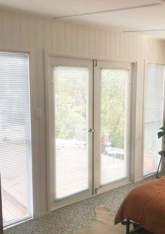 A Gray and White Striped Roman Shade Is Hanging on A Window — Bay Blinds & Doors in Umina Beach, NSW