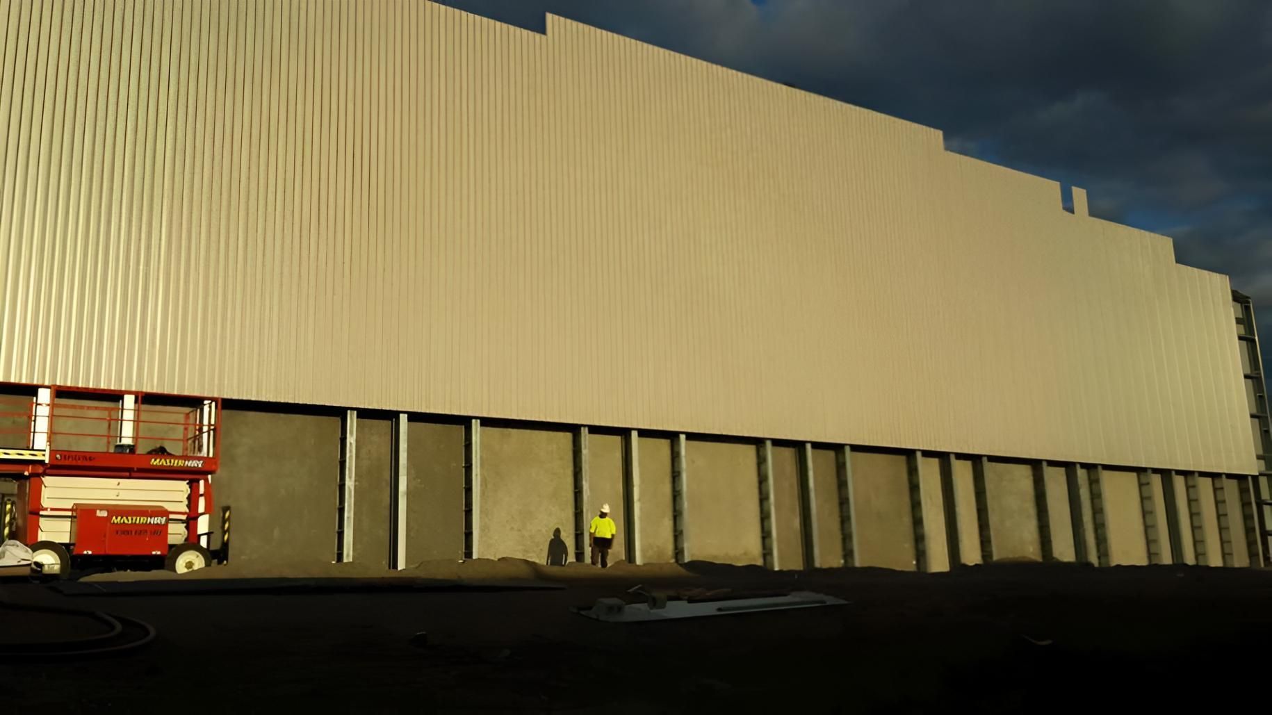 A Man in a Yellow Vest is Standing in Front of a Large Building — Geiger Solutions In Bowen Basin, QLD