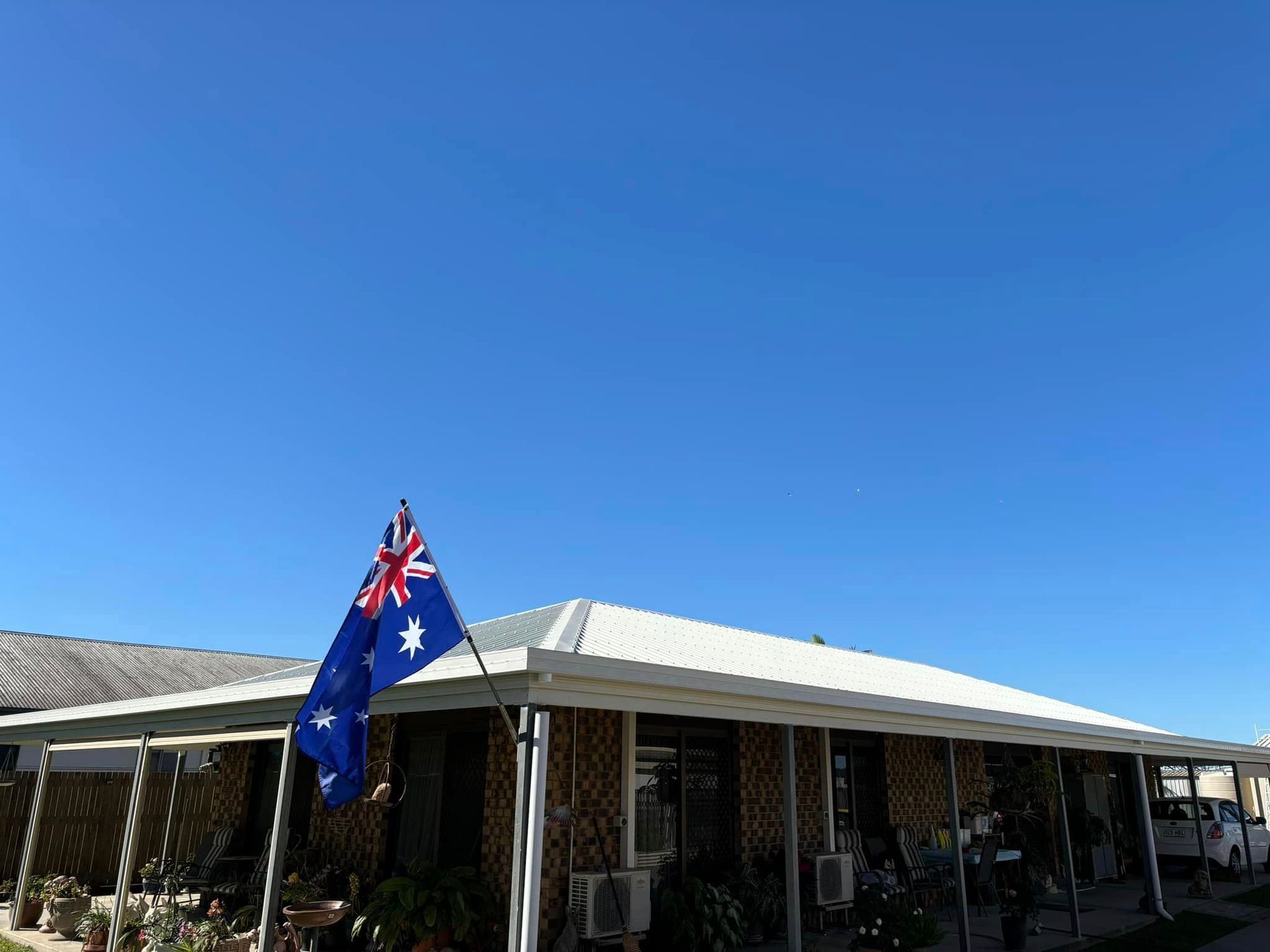 An Australian Flag is Flying in Front of a House With a White Roof — Geiger Solutions In Mackay, QLD