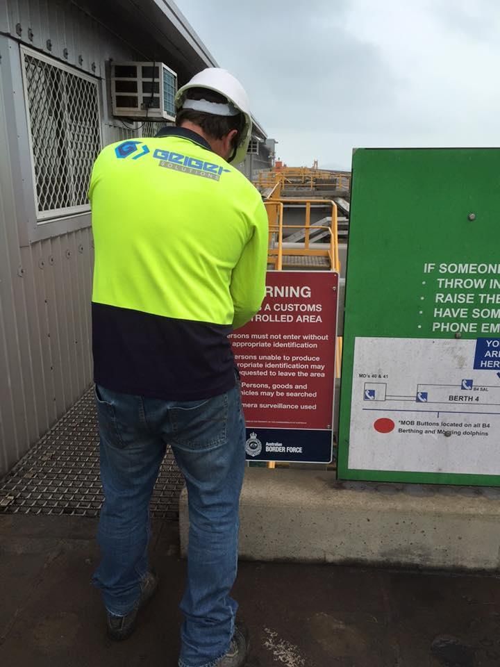 A Man in a Safety Vest is Looking at a Sign — Geiger Solutions In Emerald, QLD