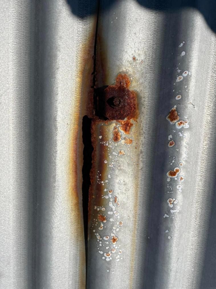 A Close Up of a Rusty Metal Wall With a Screw in It — Geiger Solutions In Mackay, QLD