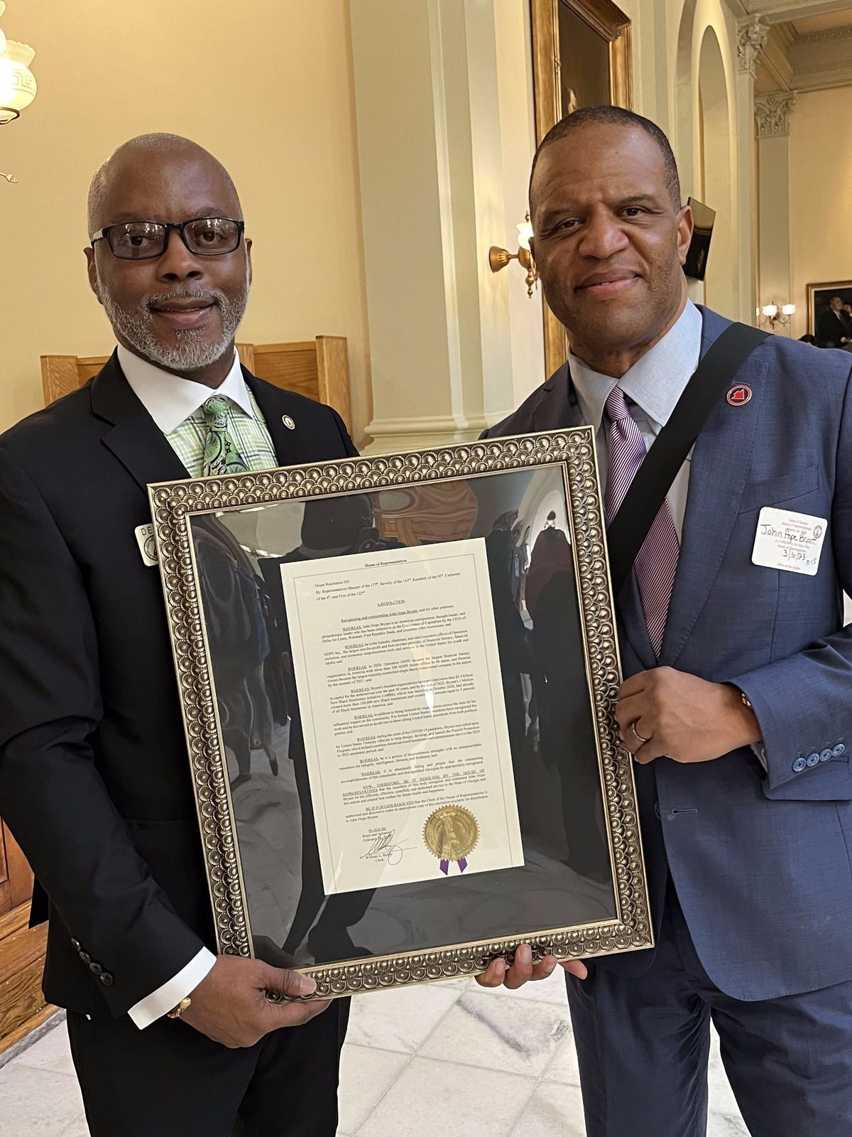 Georgia State Representative Dexter Sharper and John Hope are holding a framed certificate .